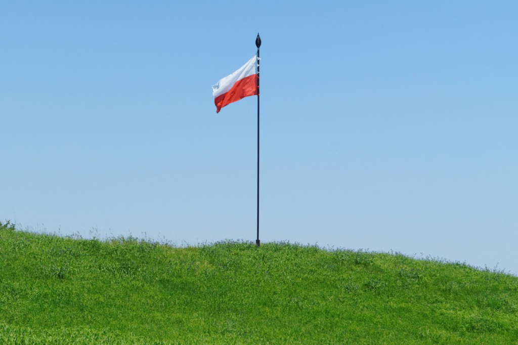 Polska flaga zatknięta na pozostałościach wału grodowego.