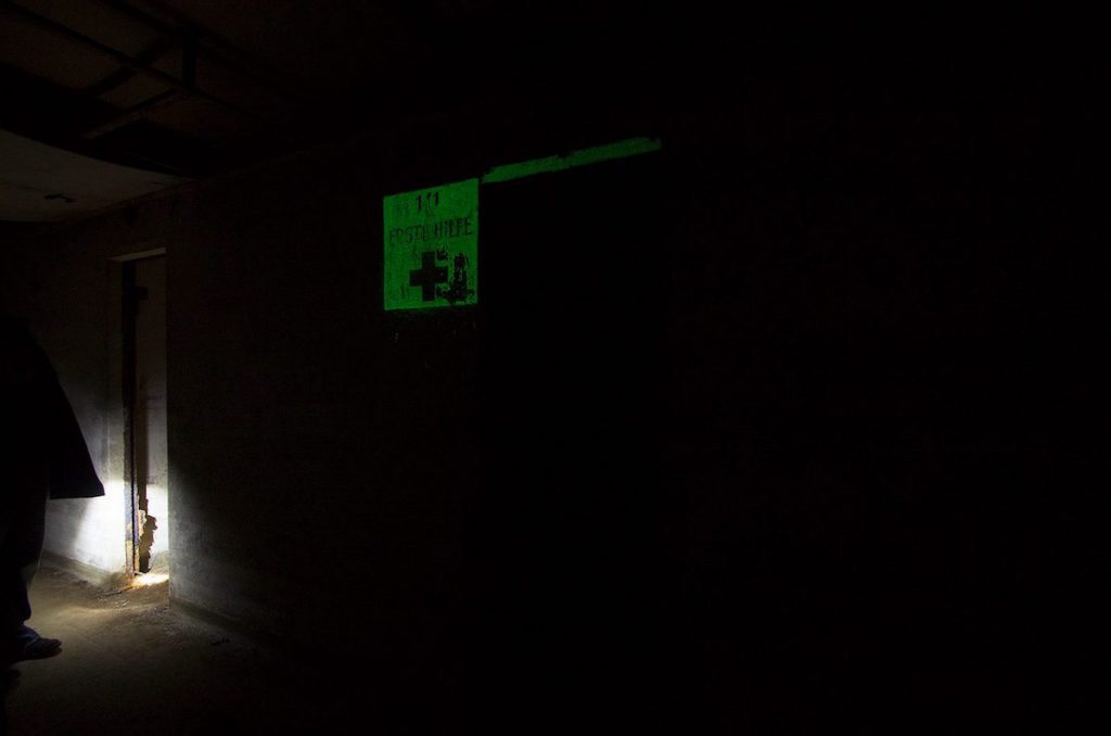 Punkt pierwszej pomocy w ciemności, napis pokryty farbą fluorescencyjną - Foto: Adrian Sitko