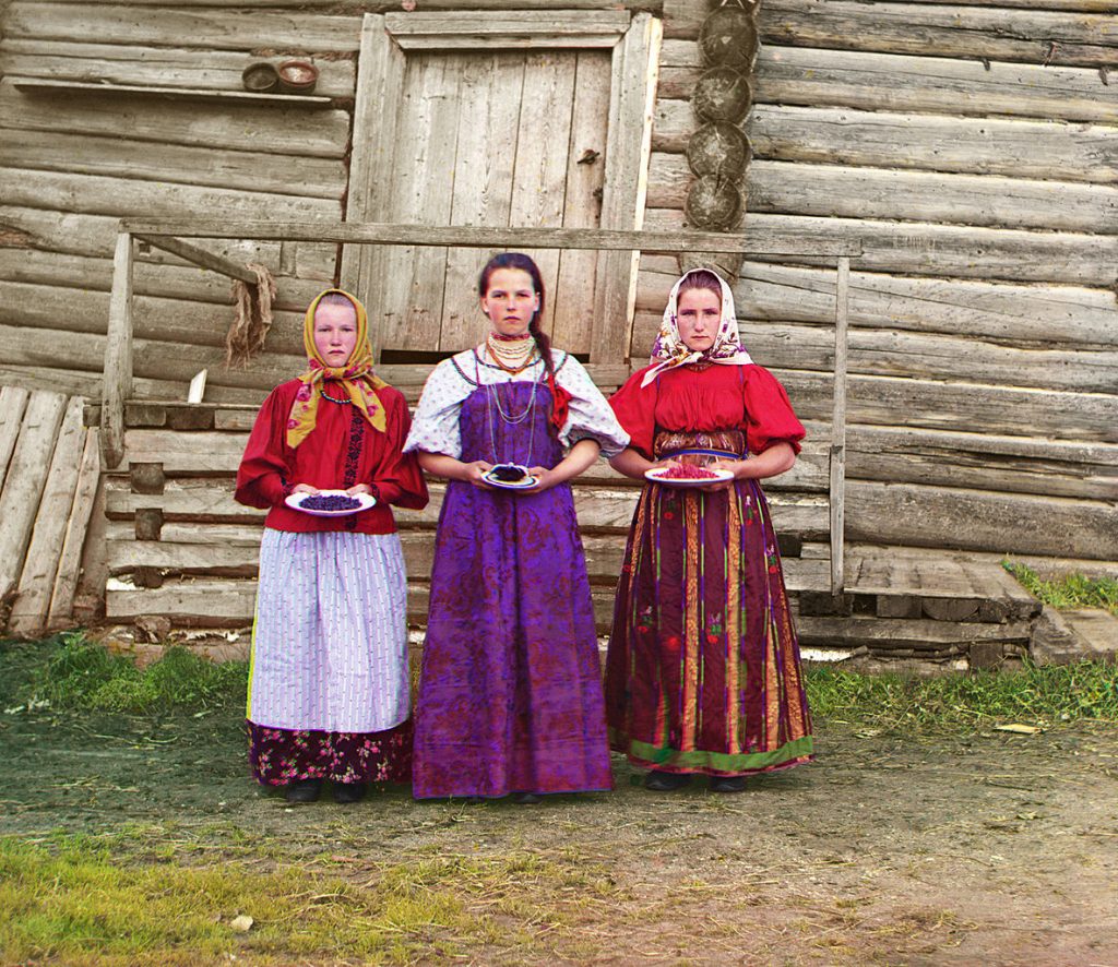 Trzy młode Rosjanki na tle tradycyjnego drewnianego domu. Rok 1909.